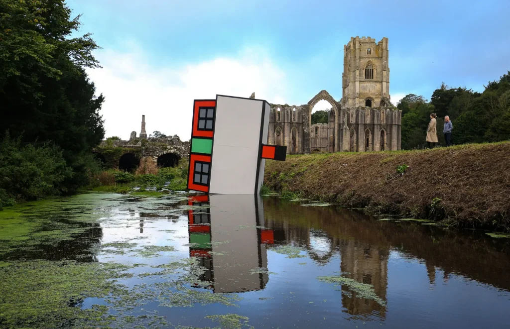 Art installation house tipped into pond